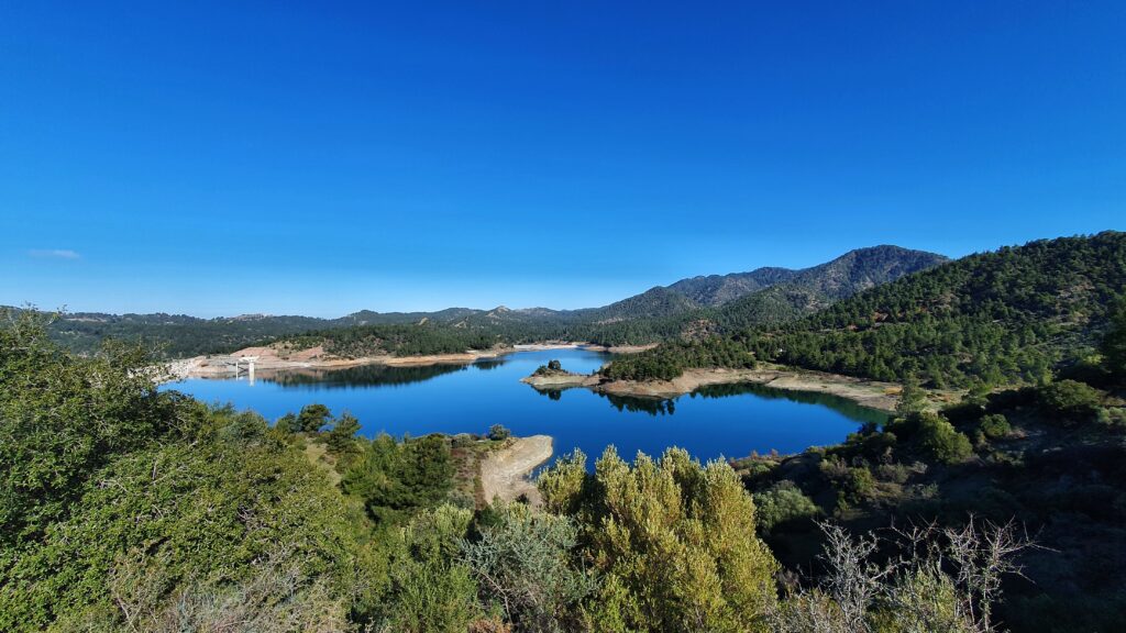 View of Kannaviou Dam and forested mountains under a clear blue sky in Cyprus